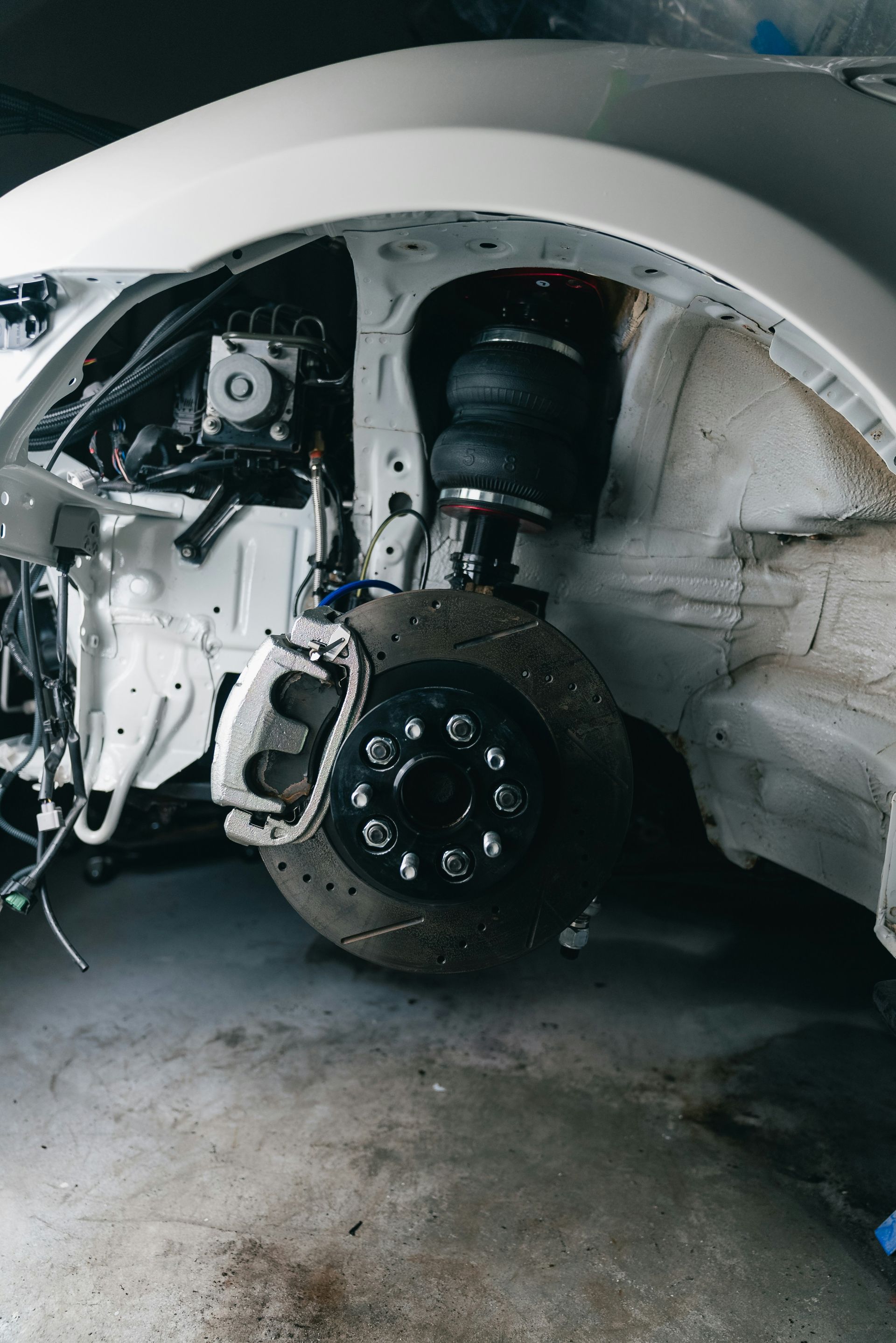 White car's disassembled front suspension and wheel assembly.