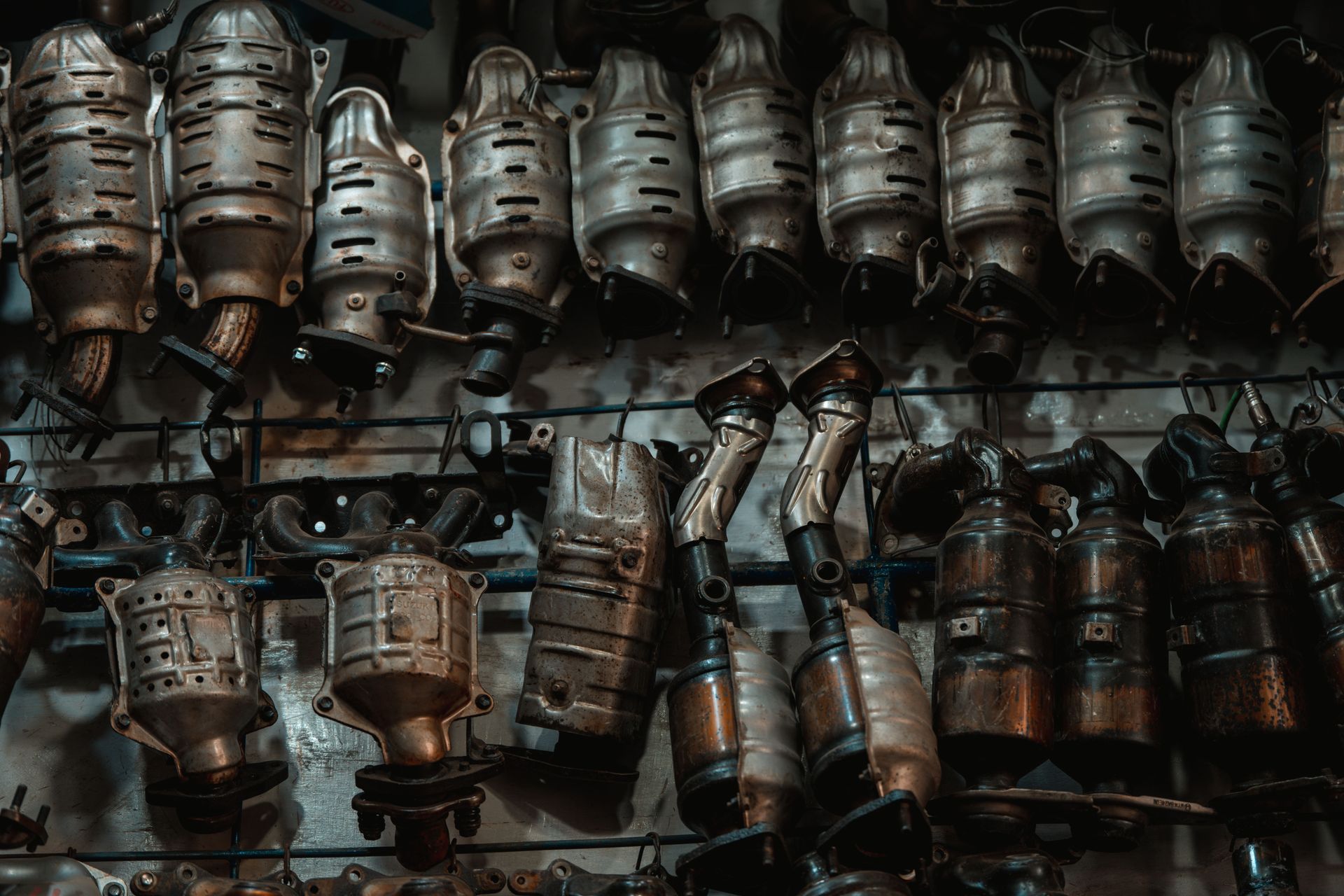 Rows of used catalytic converters in an automotive workshop setting.