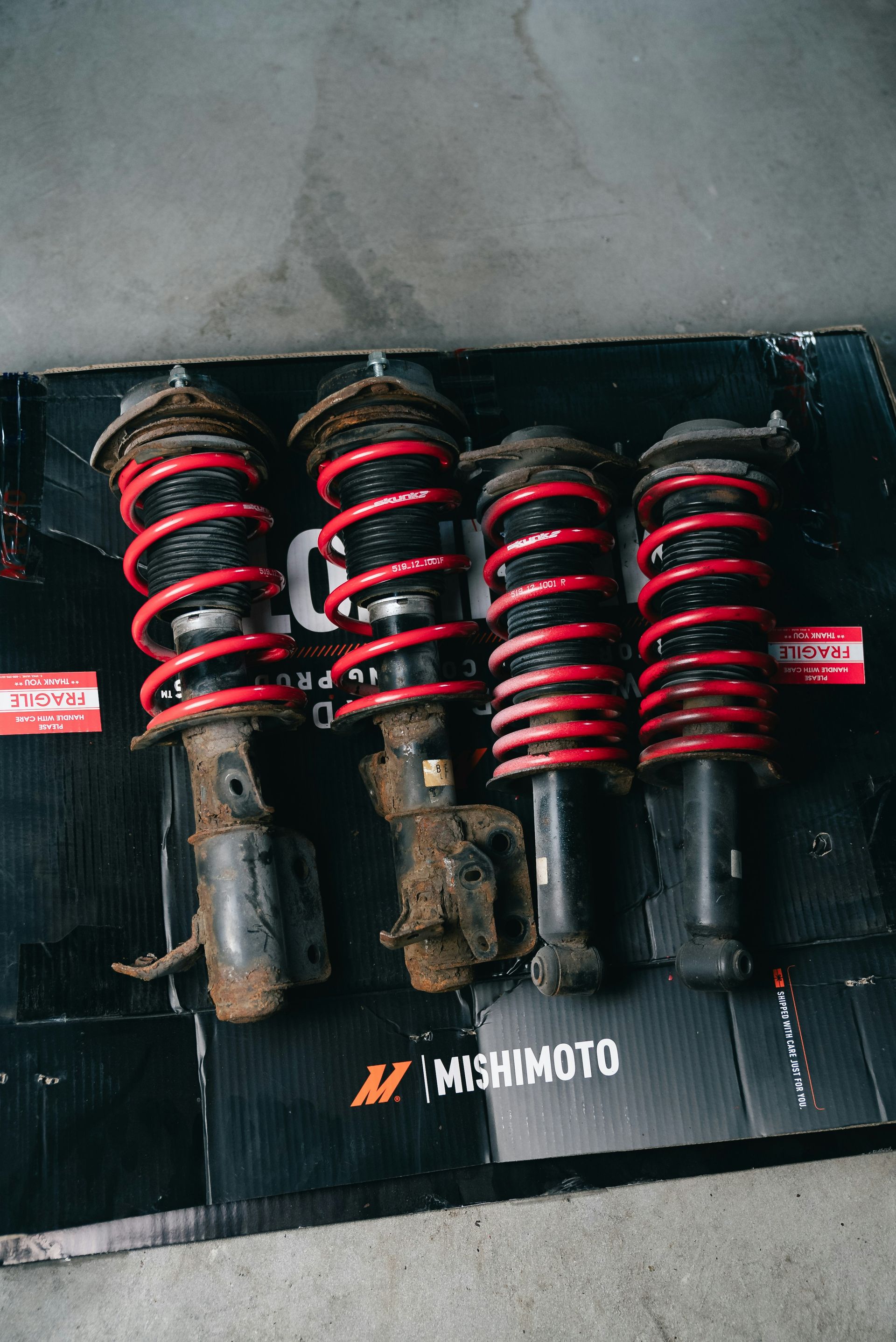 Four car suspension struts with red springs